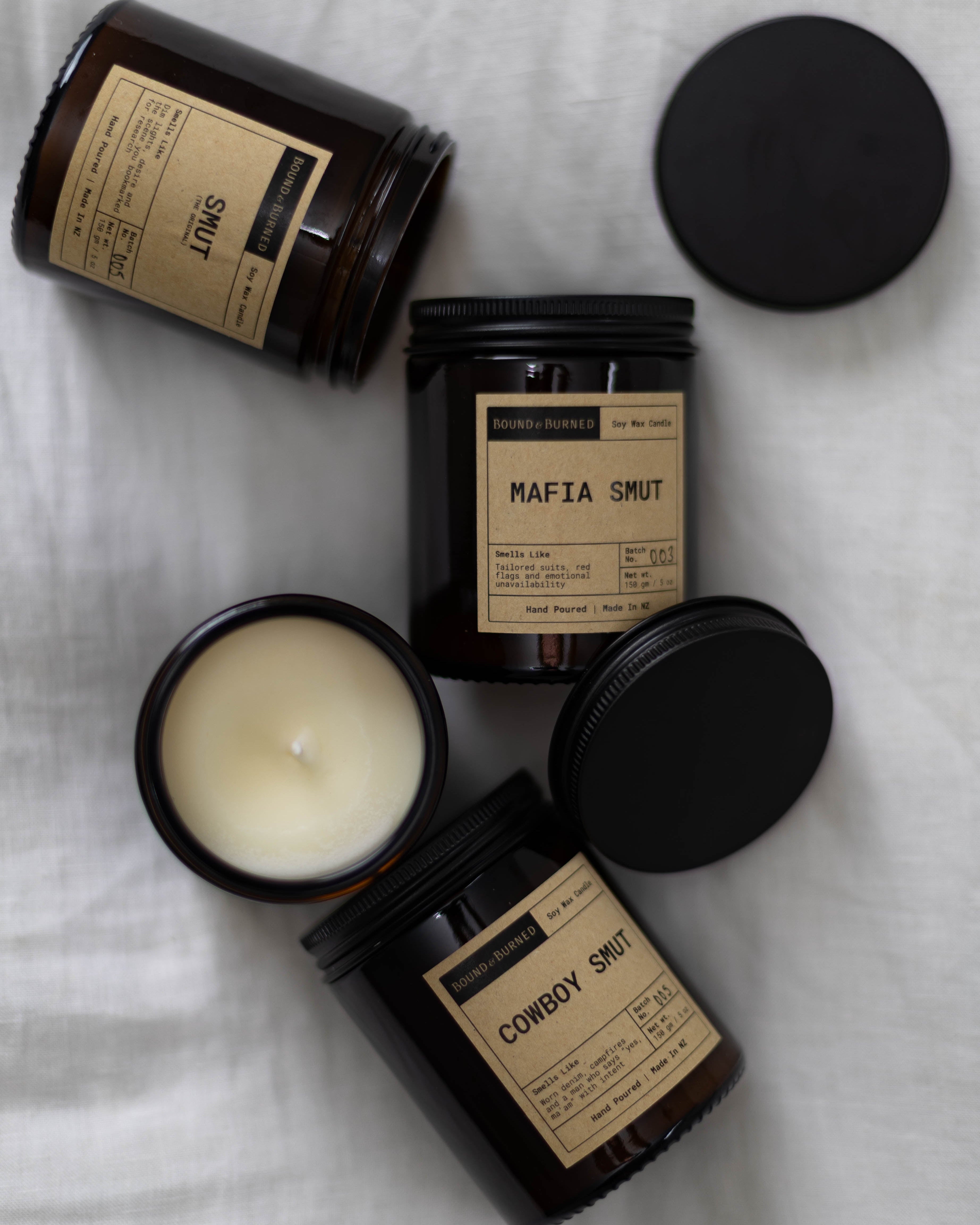 Four black candles with labels on a white surface