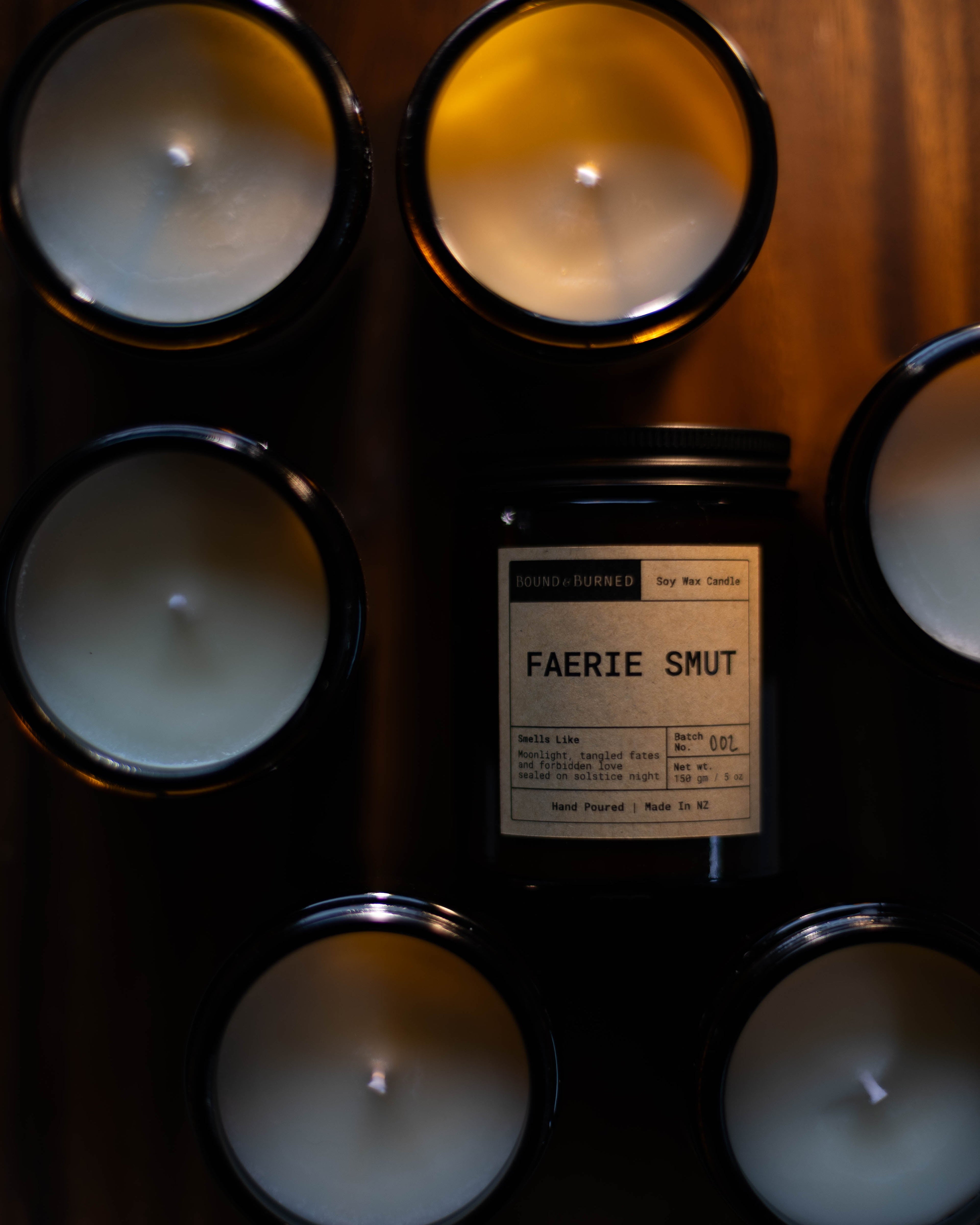 Candle holder with multiple candles and a label reading 'Faerie Smut' on a dark surface.