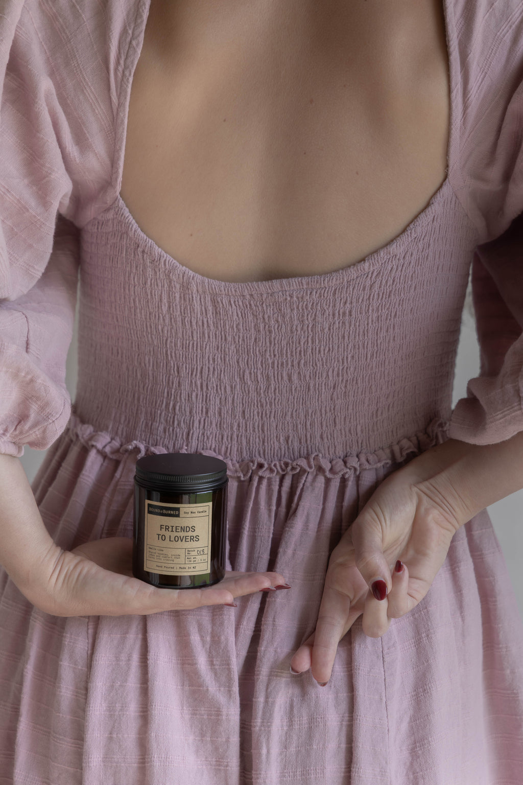 Person wearing a pink dress holding a candle with a visible label.