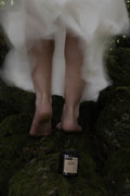 Person in a white dress standing on grass with a candle labeled 'forced proximity' nearby.