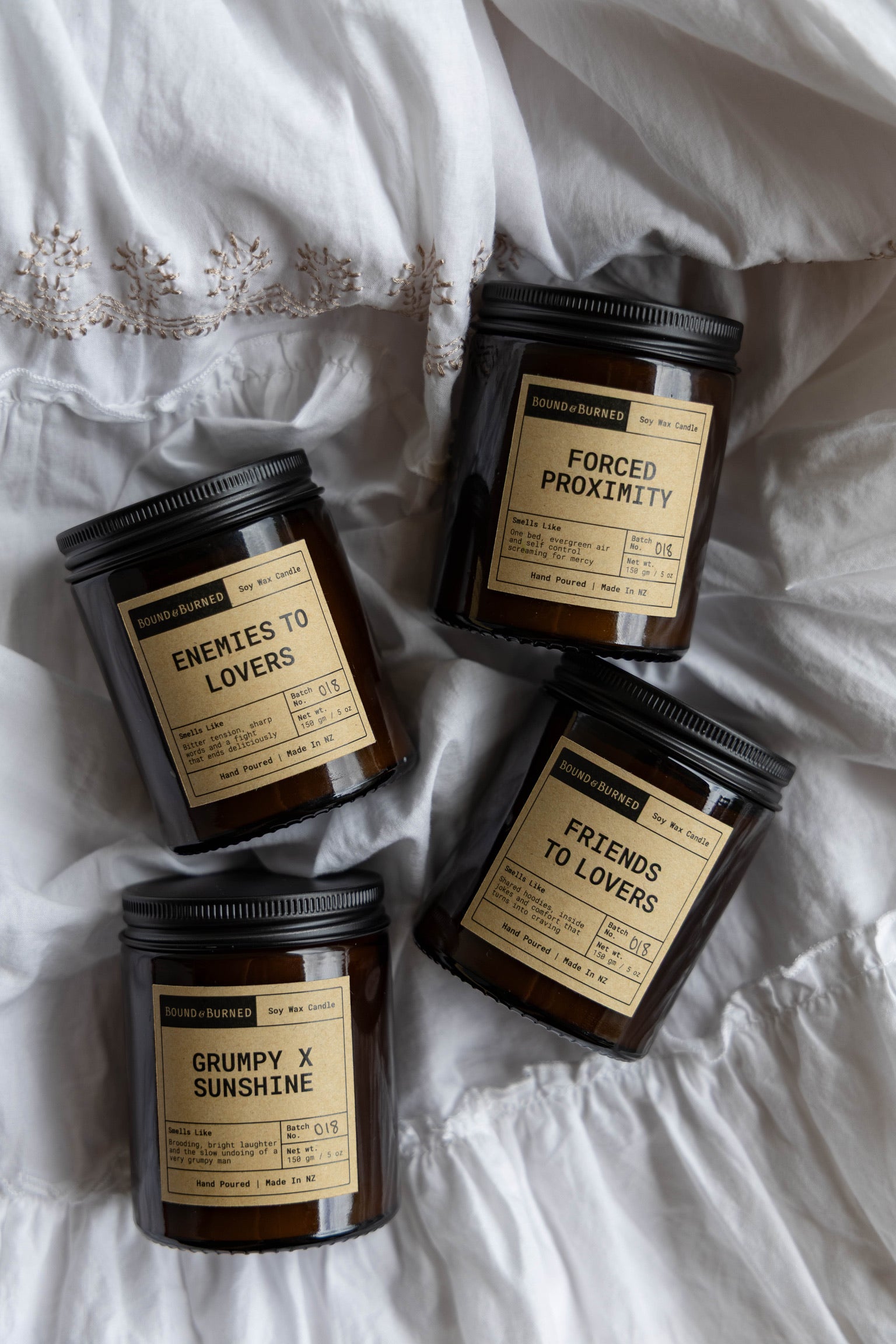 Four candles with labels on a white fabric background